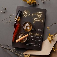 a bottle of alcohol and two glasses on top of a black card with gold lettering