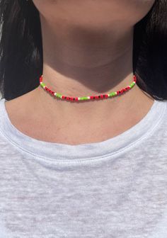 a woman wearing a red, green and yellow beaded choker on her neck