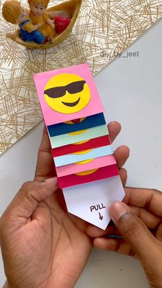 a person is holding up a card with a smiley face on it