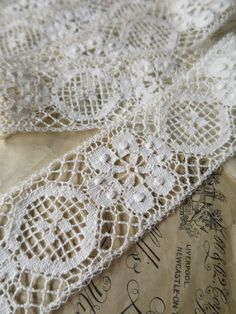 two pieces of lace sitting on top of each other next to an envelope with writing