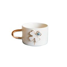 a white cup with a gold handle and an eye in the middle, on a white background