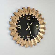 a gold and black clock on the wall with sunbursts around it's face