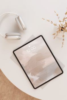 an ipad with headphones on top of it next to a plant and earbuds