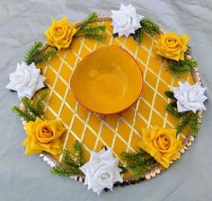 a yellow bowl sitting on top of a plate covered in flowers and greenery next to white roses