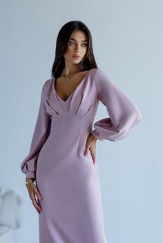 a woman in a purple dress posing with her hands on her hips and looking at the camera