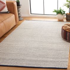 a living room area with a couch, chair and rug on the floor in front of a window