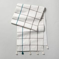 two white and green plaid towels folded on top of each other with tassels