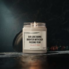 a candle that is sitting on a table with the words our love burns brighter with each passing year