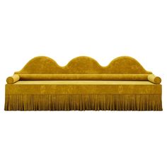 a yellow couch with fringes on the top and bottom, sitting in front of a white background