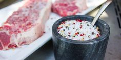 two raw meats are on the table and one is being spooned into a bowl