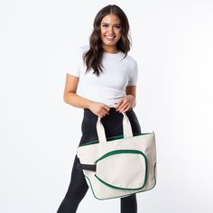 a woman holding a white and green tote bag