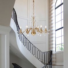 a chandelier hanging from the side of a stair case in a house with white walls