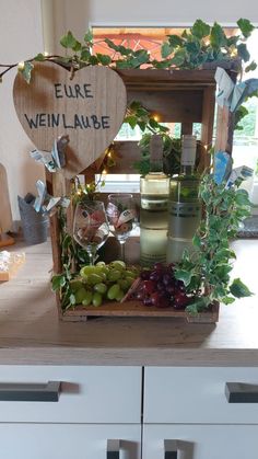 a wooden crate filled with lots of fruit and wine on top of a kitchen counter