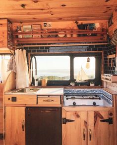 a kitchen area with sink, stove and window overlooking the ocean on a sunny day