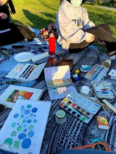 people sitting on the ground with art supplies and watercolors in front of them