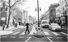 a bride and groom crossing the street at an intersection