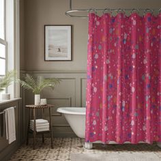 a pink shower curtain in a bathroom next to a white bathtub and window with potted plants