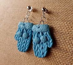 pair of blue crocheted earrings hanging from silver hooks on tan fabric background, closeup