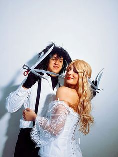 a man and woman dressed up in costumes posing for the camera with scissors on their heads