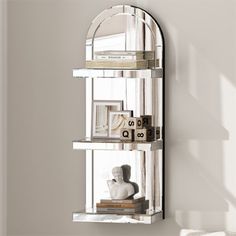 a mirror on the wall above a shelf that has books and other items in it