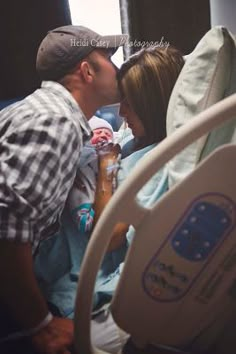 a man and woman kissing in a hospital bed with the baby laying on it's side