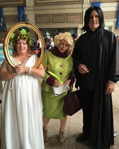 three people dressed up in costumes posing for a photo with one woman holding a mirror