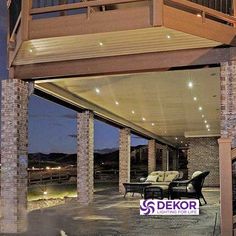 an outdoor living area with couches and chairs under a covered patio at night time