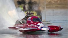 a man riding on the back of a red boat in water next to a fire hydrant