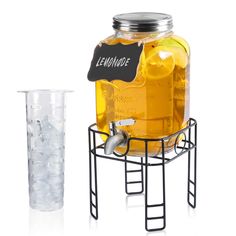 a large jar filled with yellow liquid next to a glass full of ice cubes