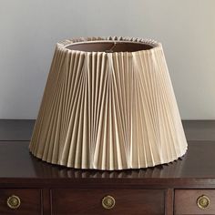 a lamp shade sitting on top of a wooden table next to a drawer with drawers