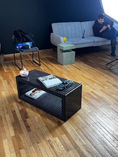 a man sitting on a couch next to a coffee table in a room with hard wood floors