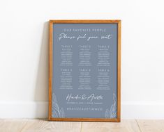 a wedding seating chart is displayed on a wooden frame in front of a white wall