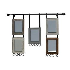 four frames hanging from a metal rail with wrought iron brackets and hooks on each side