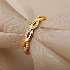 a gold ring with diamonds on top of a white cloth covered napkin, close up