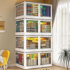 a white book shelf filled with books next to a yellow chair in a living room