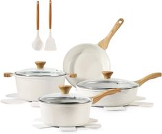 a set of white pots and pans with wooden spoons next to each other