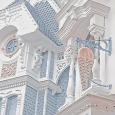 an ice cream cone is hanging from the side of a white building with blue trim