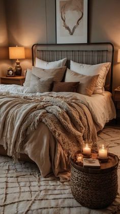 a bed with two candles on the end of it next to a night stand and nightstand