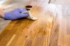 a person in blue gloves cleaning a wooden table