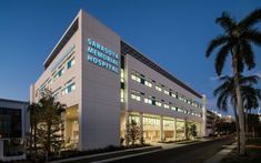 a hospital building lit up at night with palm trees