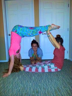 three girls are playing with each other on the floor while one girl is doing a handstand