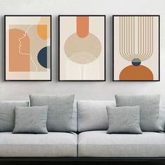 three modern art prints hanging on the wall above a gray couch in a living room