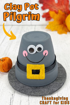 a gray hat sitting on top of a table next to an orange and yellow pumpkin