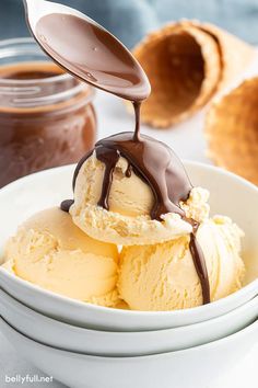 two scoops of ice cream being drizzled with chocolate on the top