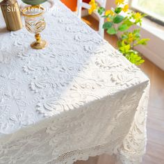 a white table cloth on top of a wooden floor next to a vase with yellow flowers