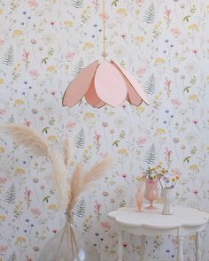 a white table topped with a vase filled with flowers next to a flower wallpaper