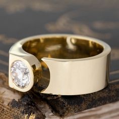 a close up of a ring with a diamond in it on a piece of wood