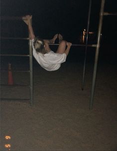 a person hanging upside down on a metal bar in the dark with their feet up