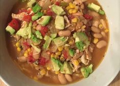 a white bowl filled with beans, avocado and other vegetables on top of a wooden table