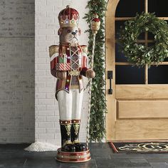 a large nutcracker statue standing in front of a door with wreath on it